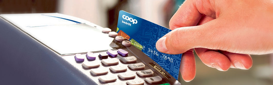 Hånd som trekker Coop kredittkort gjennom betalingsterminal